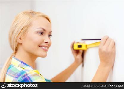 repair, building and home concept - smiling woman measuring wall