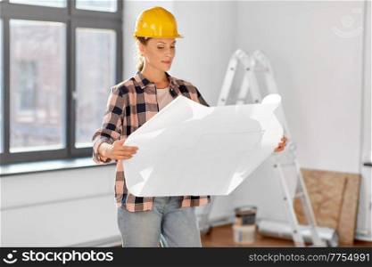 repair, building and real estate concept - woman in helmet with blueprint sitting on floor at home. woman in helmet with blueprint at home