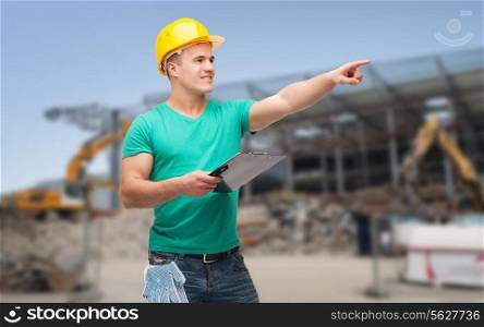 repair, building, construction and maintenance concept - smiling man in helmet with clipboard pointing finger