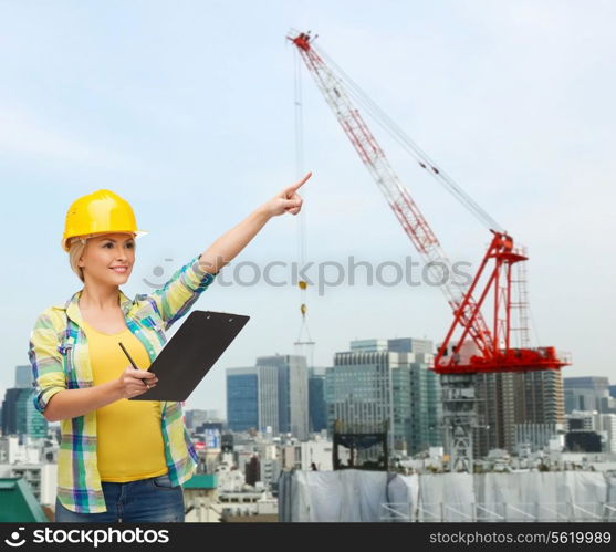 repair, building, construction, maintenance and gesture concept - smiling woman in helmet with clipboard pointing finger