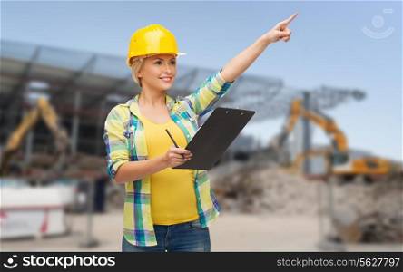 repair, building, construction, maintenance and gesture concept - smiling woman in helmet with clipboard pointing finger