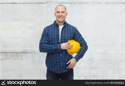 repair, building, construction, people and maintenance concept - smiling man with helmet over gray concrete wall background