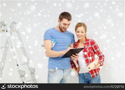 repair, building ,decoration and people concept - smiling couple with clipboard, wallpaper roll and ladder at home