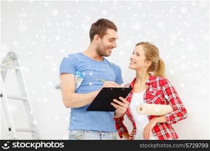 repair, building ,decoration and people concept - smiling couple with clipboard, wallpaper roll and ladder at home