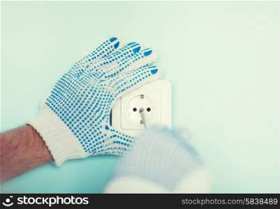 repair, building, electricity and home concept - close up of male in gloves installing new socket