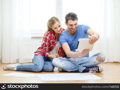 repair, building, renovation and home concept - smiling couple looking at tablet pc at home
