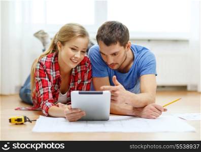 repair, building, renovation and home concept - smiling couple looking at tablet pc at home