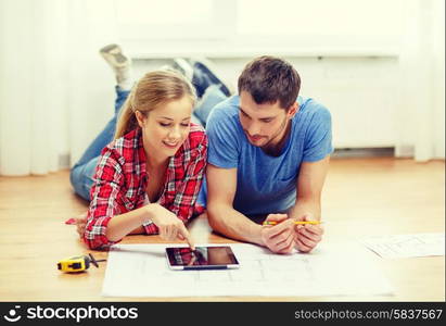 repair, building, renovation and home concept - smiling couple looking at tablet pc at home