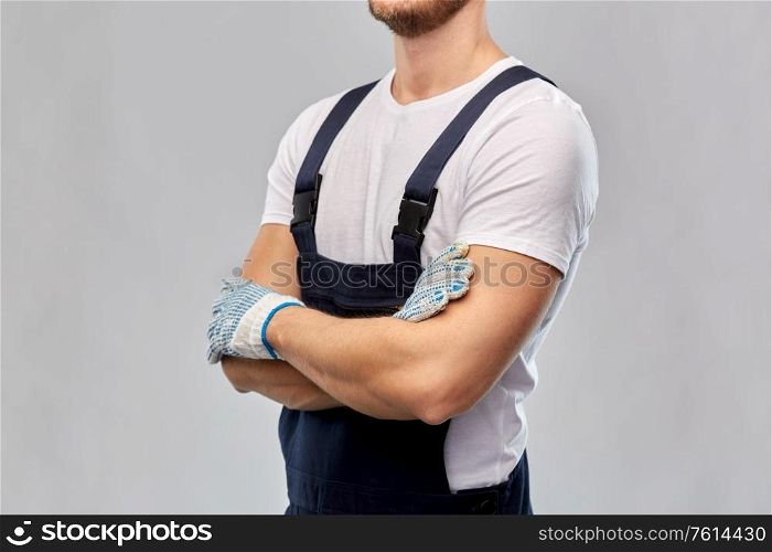 repair, construction and building - close up of male painter or builder in overall and gloves over grey background. close up of male builder in overall and gloves