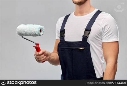 repair, construction and building - close up of painter or builder with paint roller over grey background. close up of painter or builder with paint roller