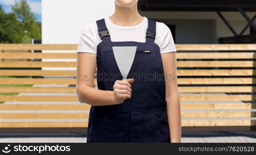 repair, construction and building concept - close up of female plasterer or builder with putty knife over living house background. close up of female builder with putty knife
