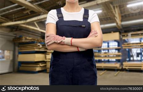 repair, construction and building concept - close up of female worker in overall over workshop at woodworking factory background. close up of female worker in overall at factory