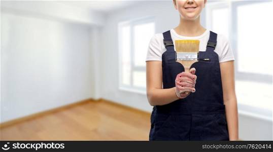 repair, construction and building concept - close up of happy smiling female painter or builder with paint brush over empty room at new home background. close up of painter or builder with paint brush