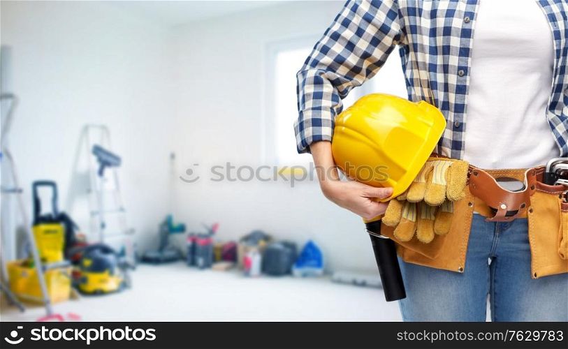 repair, construction and building concept - close up of woman or builder with helmet and working tools on belt over utility room background. woman or builder with helmet and working tools
