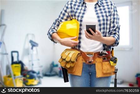 repair, construction and building concept - close up of woman or builder with smartphone, helmet and working tools on belt over utility room background. woman or builder with phone and working tools