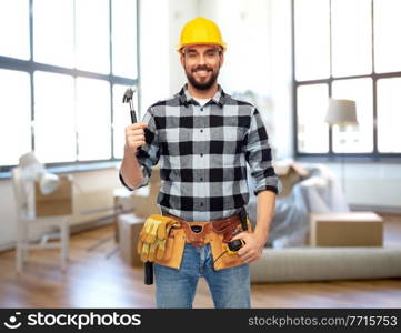 repair, construction and building concept - happy smiling male worker or builder in helmet with hammer over home room background. happy male builder in helmet with hammer at home