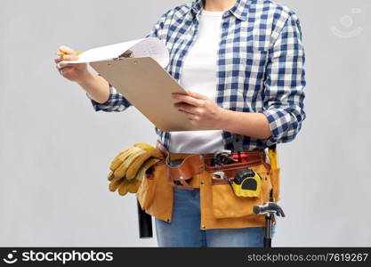 repair, construction and building concept - woman or builder with clipboard, pencil and working tools on belt over grey background. woman with clipboard, pencil and working tools