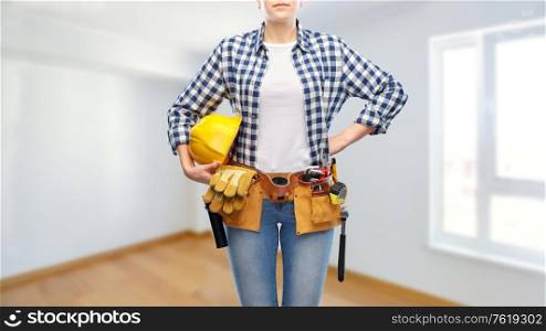 repair, construction and building concept - woman or builder with helmet and working tools on belt over empty room at new home background. woman or builder with helmet and working tools