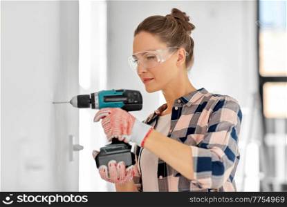 repair, construction and building concept - woman or builder with perforator drilling wall at home. woman with perforator drilling wall at home