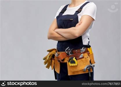 repair, construction and building concept - woman or builder with working tools on belt over grey background. woman or builder with working tools on belt