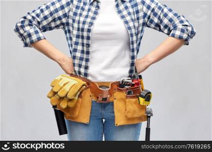repair, construction and building concept - woman or builder with working tools on belt over grey background. woman or builder with working tools on belt