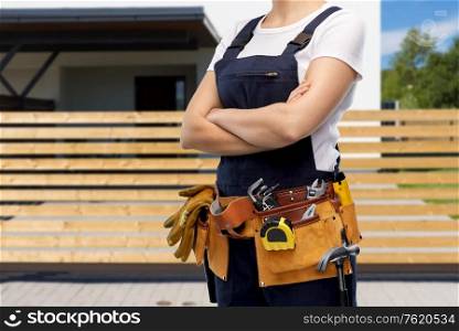 repair, construction and building concept - woman or builder with working tools on belt over living house background. woman or builder with working tools on belt