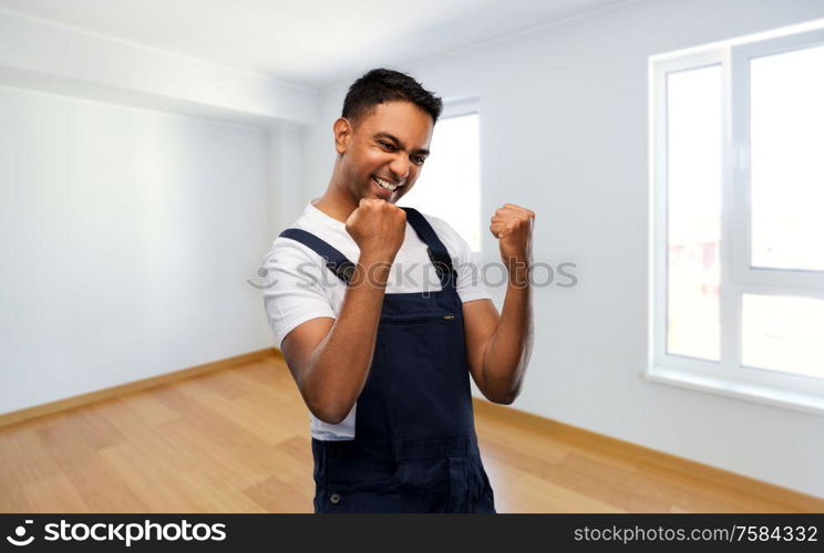repair, construction and building - happy smiling indian builder or repairman celebrating success over new home empty room background. indian builder celebrating success at new home