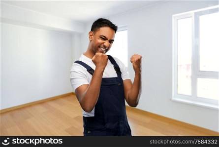 repair, construction and building - happy smiling indian builder or repairman celebrating success over new home empty room background. indian builder celebrating success at new home