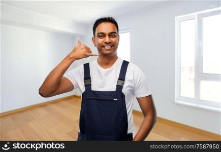 repair, construction and building - happy smiling indian builder or repairman making phone call gesture over new home empty room background. builder making phone call gesture at new home