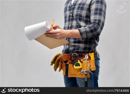 repair, construction and building - male worker or builder with clipboard, pencil and working tools on belt over grey background. builder with clipboard, pencil and working tools