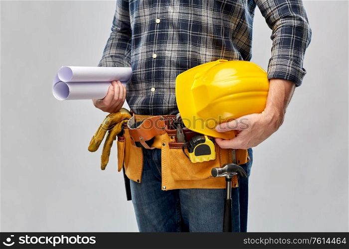 repair, construction and building - male worker or builder with helmet, blueprint and working tools on belt over grey background. builder with helmet, blueprint and working tools