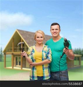 repair, construction and maintenance concept - smiling couple with hammer and drill over white background