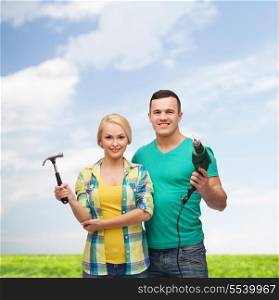 repair, construction and maintenance concept - smiling couple with hammer and drill over white background