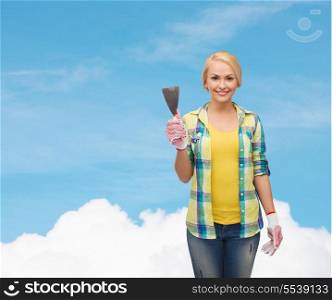repair, construction and maintenance concept - smiling female worker in gloves with spatula