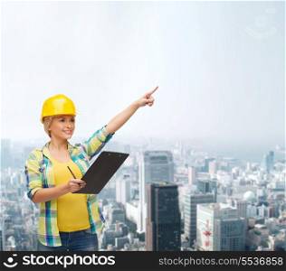repair, construction and maintenance concept - smiling woman in helmet with clipboard pointing finger