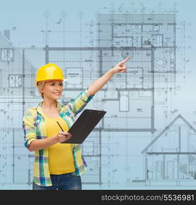 repair, construction and maintenance concept - smiling woman in helmet with clipboard pointing finger