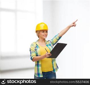 repair, construction and maintenance concept - smiling woman in helmet with clipboard pointing finger
