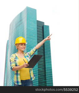 repair, construction and maintenance concept - smiling woman in helmet with clipboard pointing finger