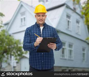 repair, construction, building, people and maintenance concept - smiling male builder or manual worker in helmet with clipboard taking notes over living house background