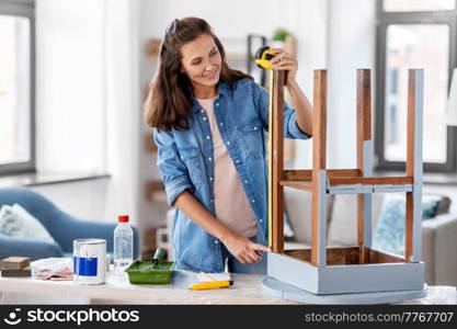 repair, diy and home improvement concept - happy smiling woman with ruler measuring old wooden table for renovation. woman with ruler measuring table for renovation