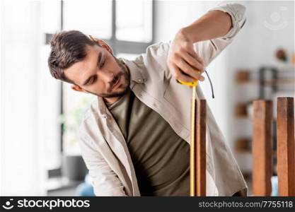 repair, diy and home improvement concept - man with ruler measuring old round wooden table for renovation. man with ruler measuring table for renovation