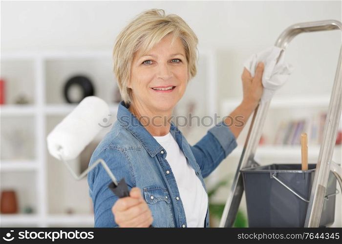 repair home elderly woman holding paint roller for wallpaper