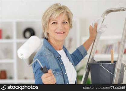 repair home elderly woman holding paint roller for wallpaper