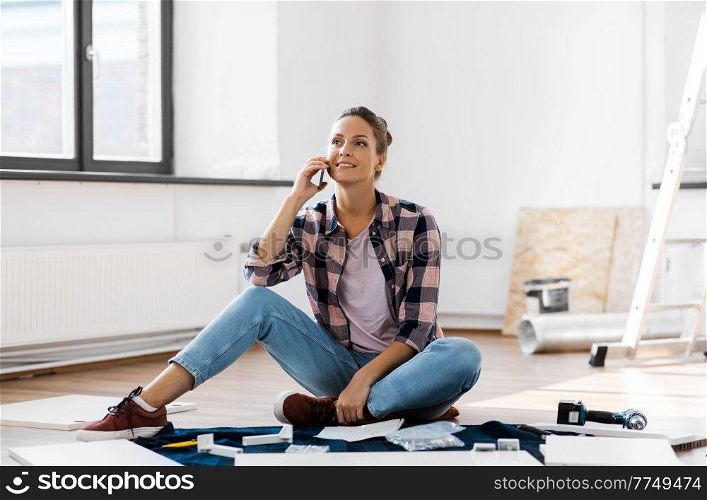 repair, improvement and furniture concept - happy smiling woman assembling new locker and calling on smartphone at home. woman assembling furniture and calling on phone