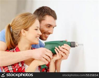 repair, interior design, building, renovation and home concept - smiling couple drilling hole in wall at home