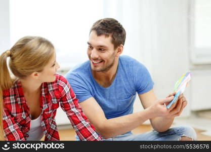 repair, interior design, building, renovation and home concept - smiling couple looking at color samples at home