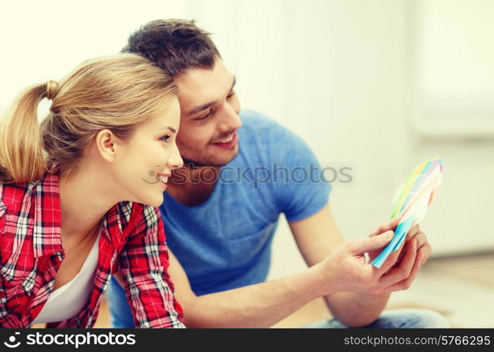 repair, interior design, building, renovation and home concept - smiling couple looking at color samples at home