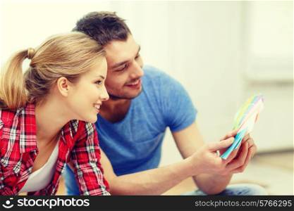 repair, interior design, building, renovation and home concept - smiling couple looking at color samples at home