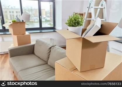 repair, moving and real estate concept - sofa and corrugated boxes with stuff at new home. sofa and corrugated boxes with stuff at new home
