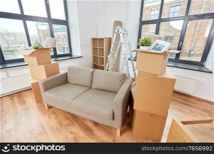 repair, moving and real estate concept - sofa and corrugated boxes with stuff at new home. sofa and corrugated boxes with stuff at new home